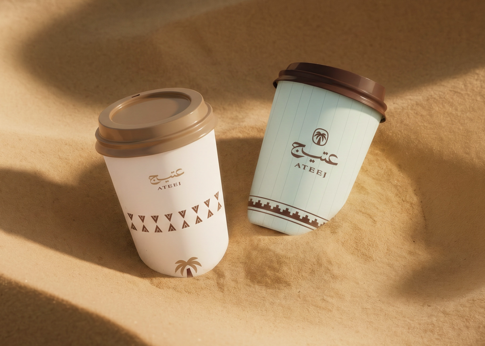 Two Ateej branded cups resting in desert sand